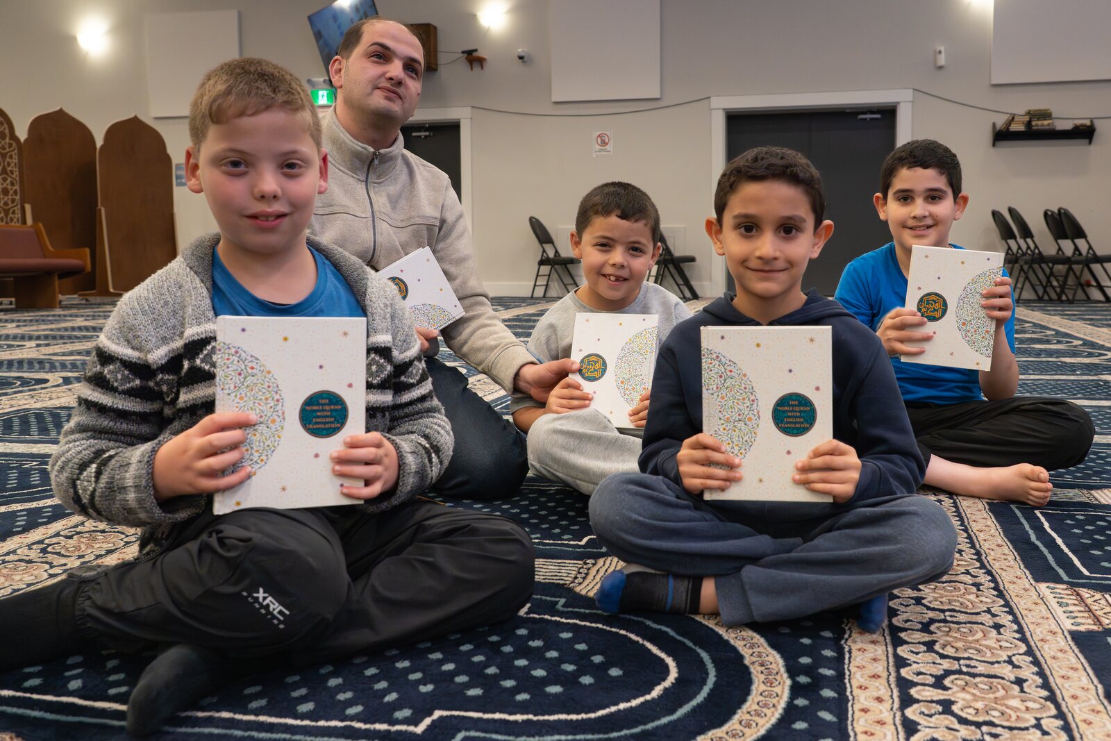 Two boys holding the Qur'ans they received.