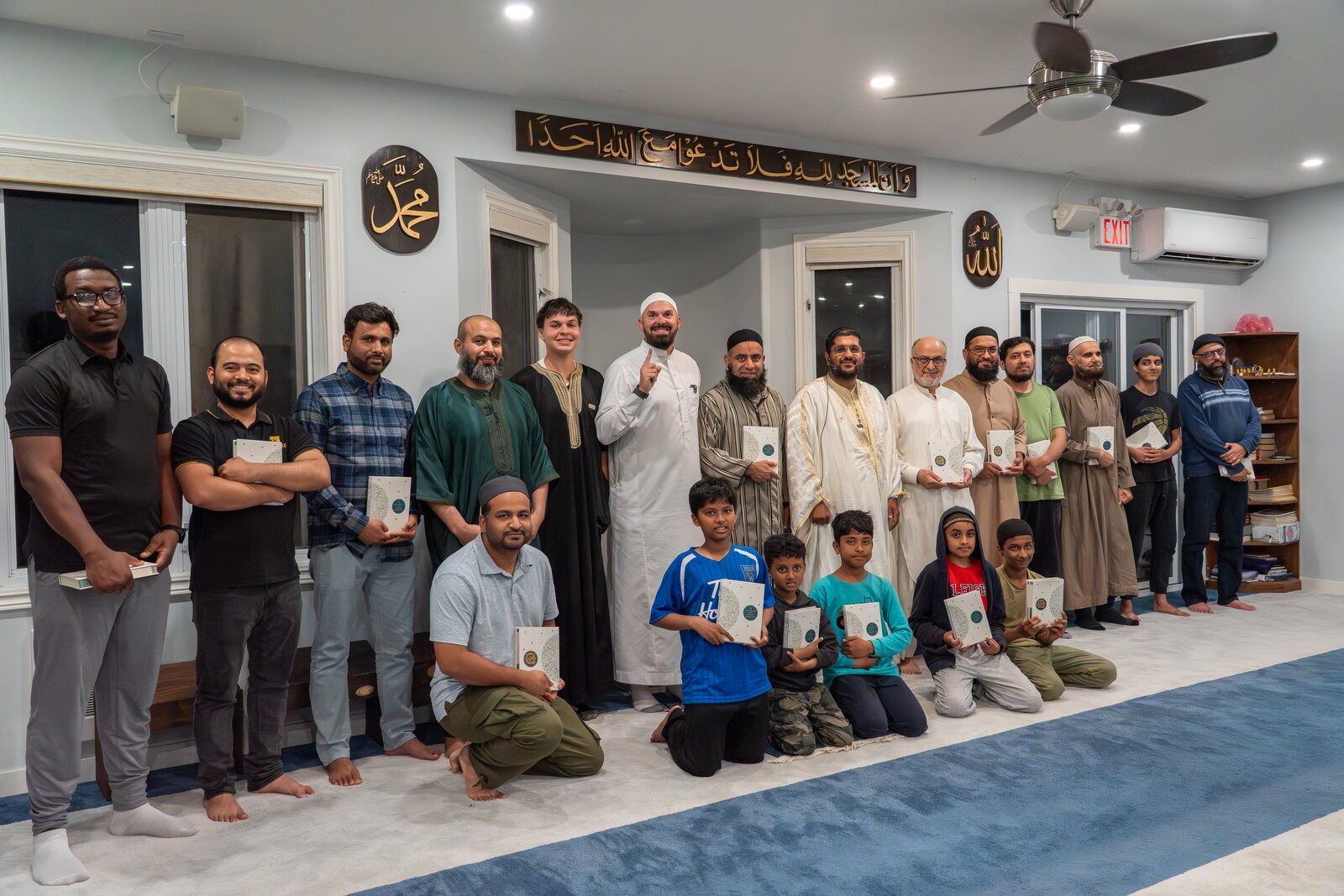 A community gathered together, each holding a Qur'an.